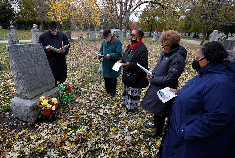Father Greg Rom, far left, leads a prayer service at the grave of Martha Jane Chisley Tolton, mother of Venerable Father Augustus Tolton.